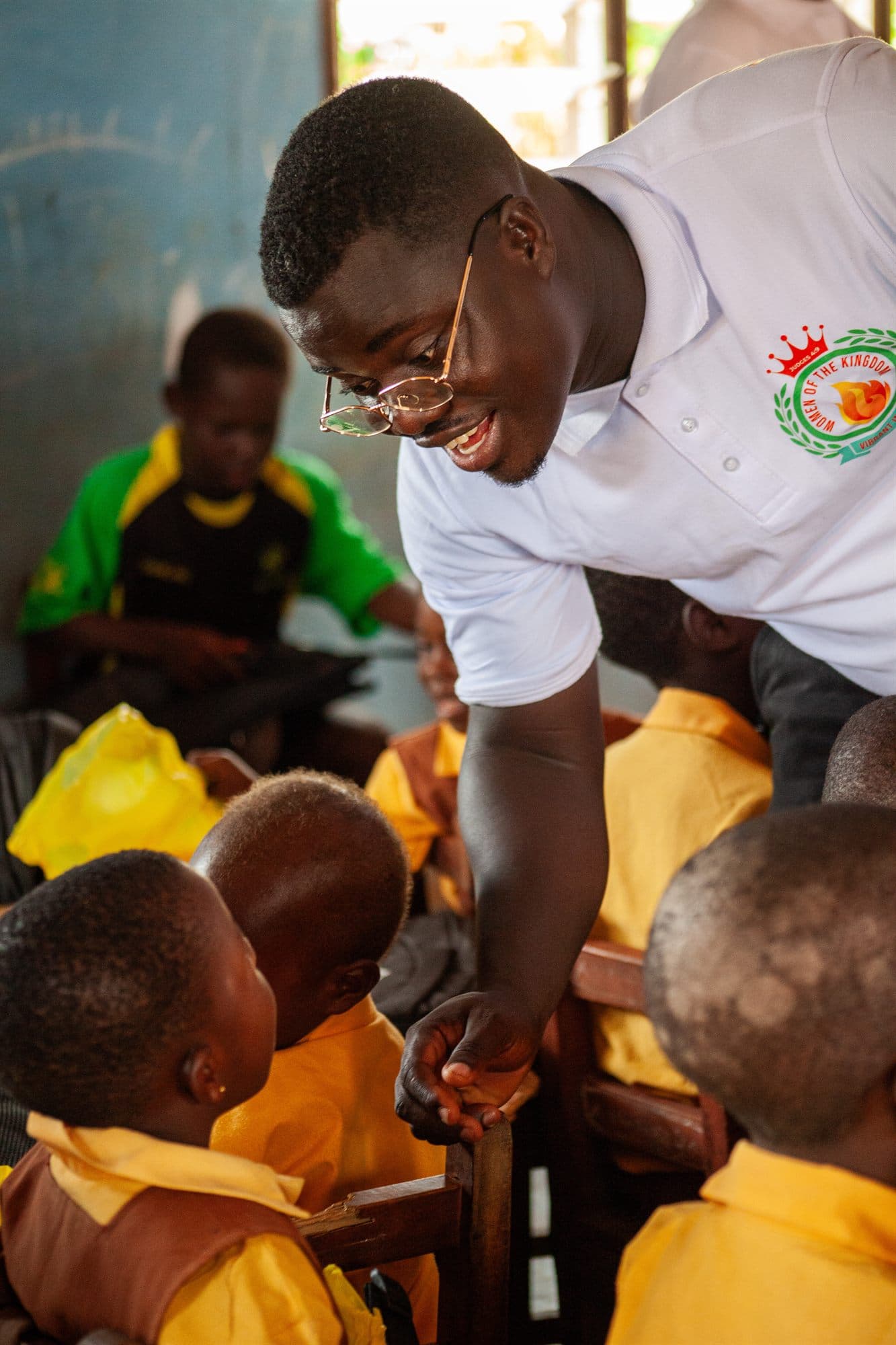 A Women of the Kingdom volunteer handing school supplies to children in a classroom