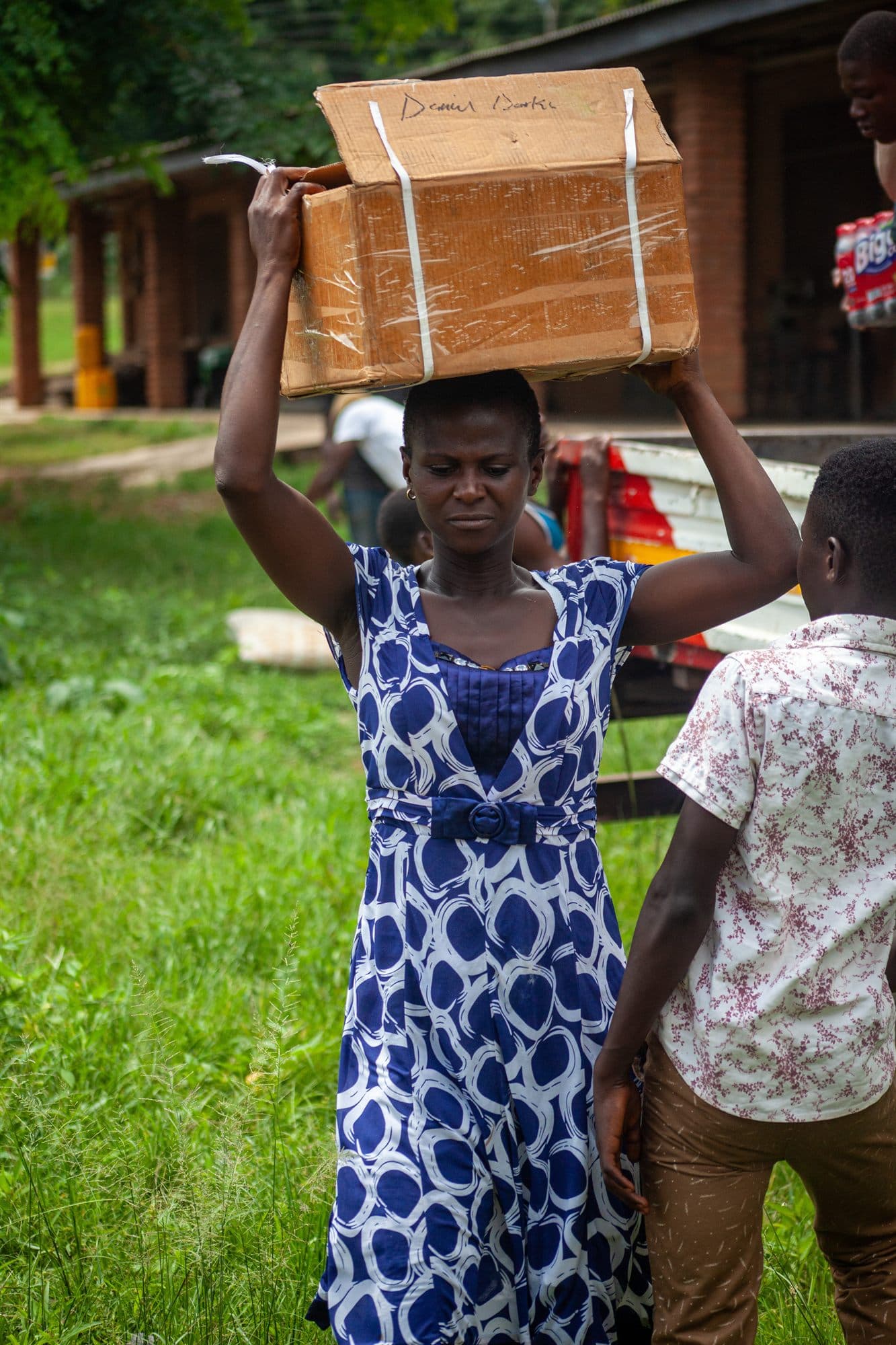 A community member carrying a box of donated supplies on her head