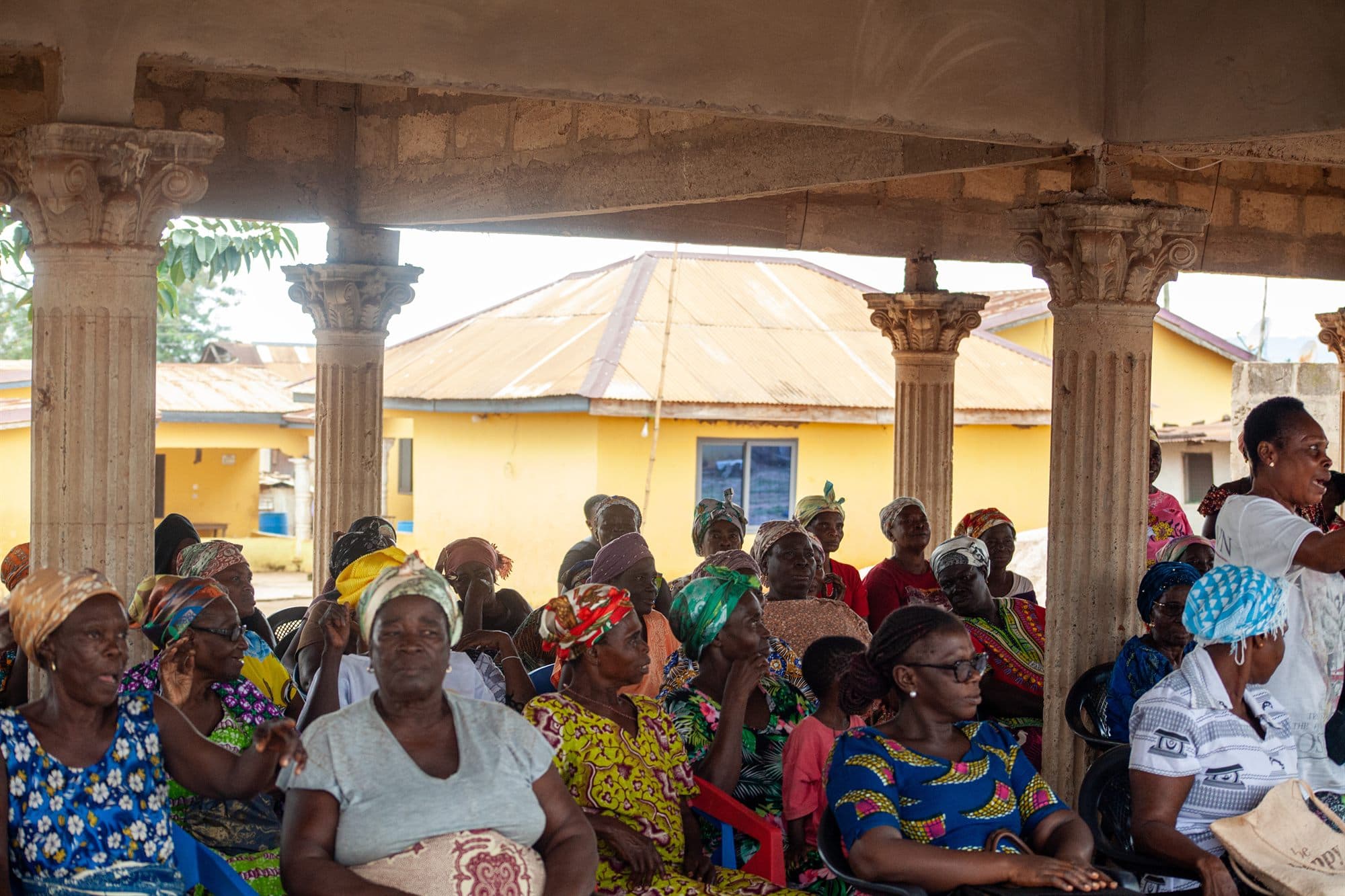 Women of the community seated together under a pavilion at an outreach gathering